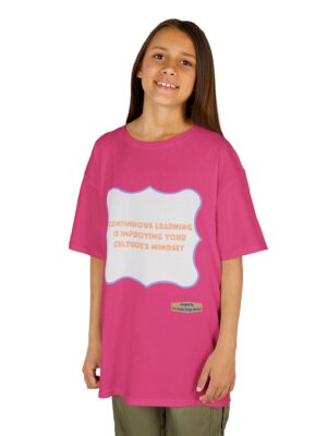 Girl in a bright pink oversized T-shirt smiling at the camera, with a white badge-shaped graphic outlined in blue on the chest containing orange text.
