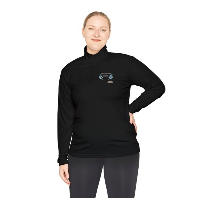 Woman wearing a black long-sleeve athletic top with a small blue laurel emblem on the left chest, standing with one hand on her hip.