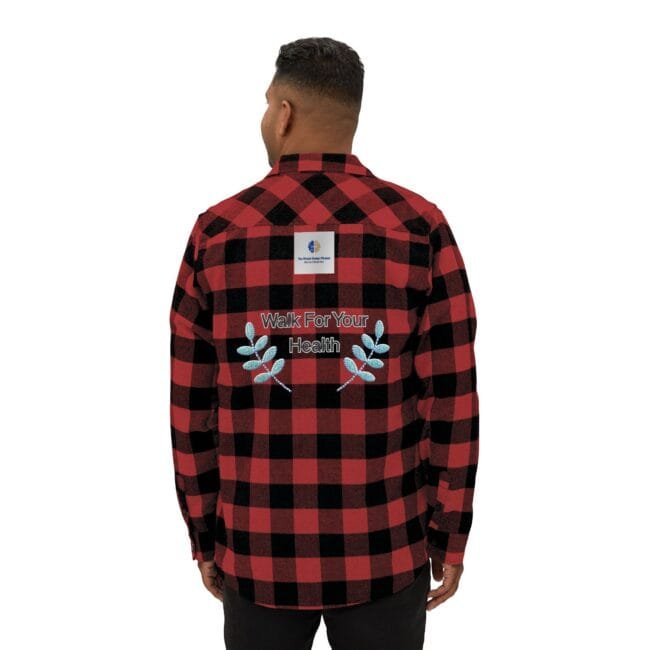 Back view of a person in a red-and-black plaid shirt with an embroidered 'Walk For Your Health' message and decorative blue leaves on the back.
