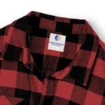 Red and black plaid flannel shirt collar with a white square brand tag on the chest area.