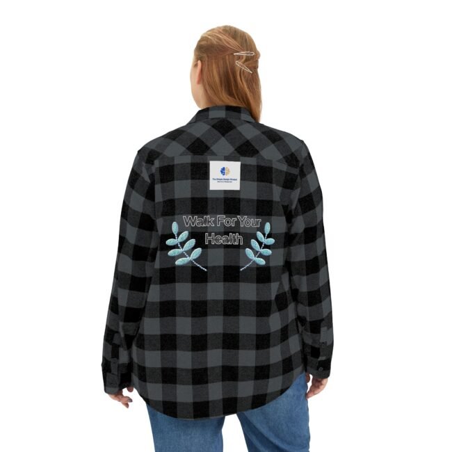 Back view of a person wearing a black-and-gray plaid flannel shirt with embroidery reading 'Walk For Your Health' and blue leaf designs.