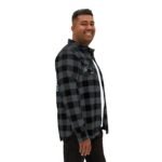 Man in a black and gray plaid flannel shirt, shown in a side profile with a smile.