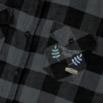 Close-up of a dark gray plaid shirt pocket with embroidery: 'Walk For Your Health' and blue leaf accents.