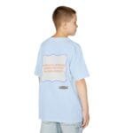 Back view of a light-blue T-shirt on a boy, with a white framed back graphic that reads 'Continuous learning is improving your culture's mindset'.