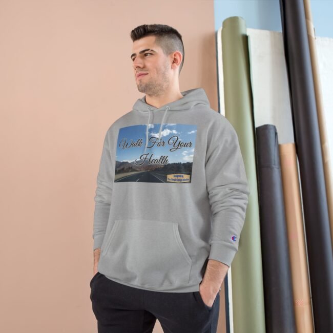 Man wearing a light gray hoodie stands with hands in pockets; the front graphic reads 'Walk For Your Health' over a road scène background in a studio setting.