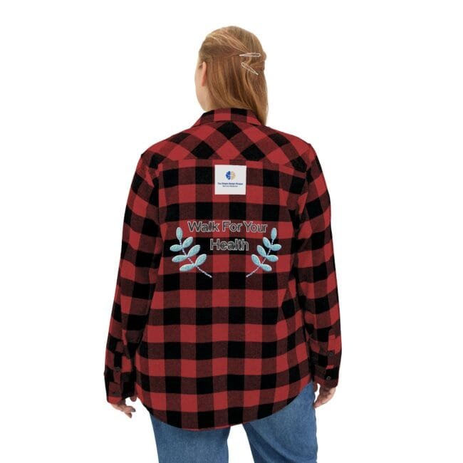 Back view of a person wearing a red-and-black plaid flannel with an embroidered 'Walk For Your Health' slogan and decorative leaves on the back, plus a small logo patch near the collar.