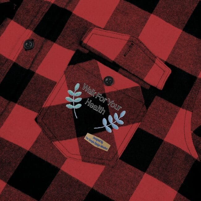 Red and black plaid flannel shirt pocket with embroidered 'Walk For Your Health' slogan and blue leaf accents.