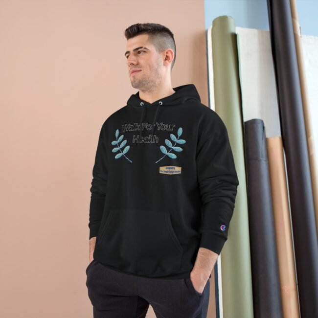 Man in a black hoodie with the text “Walk For Your Health” and blue leaf embroidery, standing indoors against a peach wall.