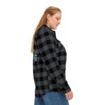Side view of a woman wearing a black and gray plaid flannel shirt with blue floral embroidery on the back, paired with blue jeans