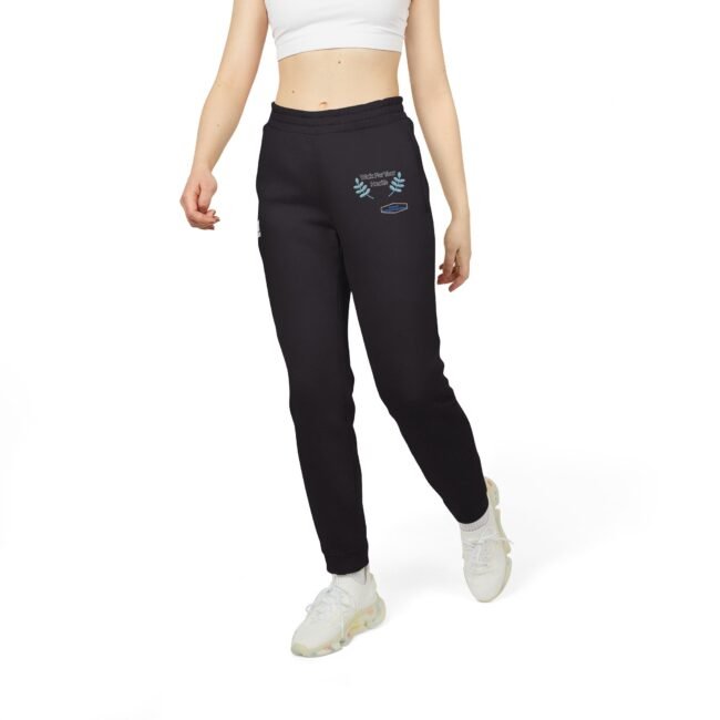 Model wearing black joggers with blue embroidered design on the left thigh, paired with a white crop top and white sneakers.