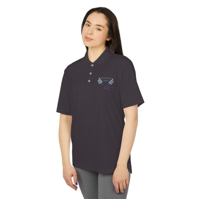 Woman wearing a dark polo shirt with short sleeves, featuring light blue embroidered laurel wreath and a small badge on the chest.
