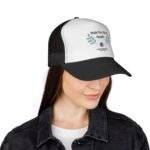 Close-up of a person wearing a black-and-white trucker hat and a dark denim jacket, shown from the shoulders up.