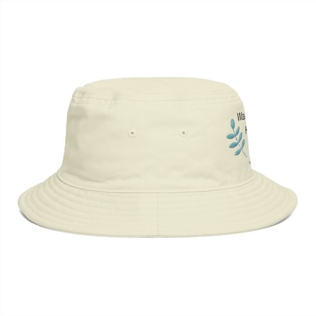 Cream bucket hat with stitched brim and blue-green leaf embroidery on the side, close-up view.