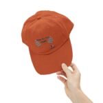 Orange baseball cap being held by a hand against a white background, with embroidered text 'Walk For Your Health' and teal leaf graphics on the front.