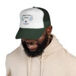 White trucker cap with the text 'Walk For Your Health' and leafy blue-green graphics on the front, worn by a person in a beige hoodie.