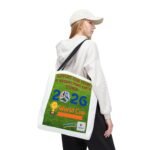 Side profile of a young woman in a white hoodie and cap carrying a white tote bag with a World Cup poster image.
