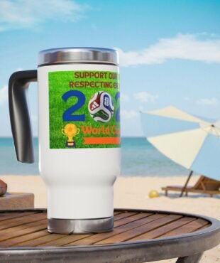 Close-up of a white mug with a bright green World Cup sticker and soccer ball artwork, placed on a wooden table at the beach