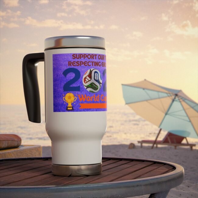 White travel mug with a purple World Cup sticker on a wooden table at the beach, with umbrellas in the background