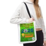 Person wearing a white hoodie with a black strap bag across the chest and a bright green poster pinned to the front saying 'Support Our Team' and related World Cup graphics.