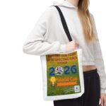 Person wearing a white hoodie with a black shoulder strap carrying a bag with a bright poster that says "World Cup 2026"