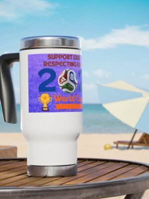 3755281386768532130_2048jpeg White travel mug with a purple World Cup sticker and soccer ball graphic on a wooden table at the beach