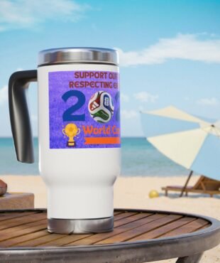 White travel mug with a purple World Cup sticker and soccer ball graphic on a wooden table at the beach