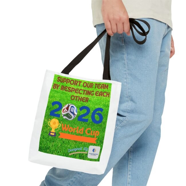 Person wearing a light shirt and jeans holds a white tote bag featuring a bright green poster about the 2026 World Cup and a soccer graphic in the corner.