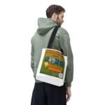 Side-profile of a man in a green hoodie carrying a white tote bag with a colorful poster design visible on it.