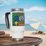 White travel mug on a wooden table at the beach, displaying a colorful World Cup sticker and blue sky in the background.