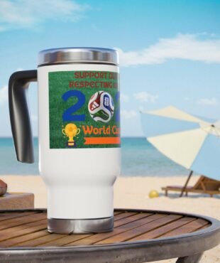 White travel mug on a wooden table at the beach, displaying a colorful World Cup sticker and blue sky in the background.