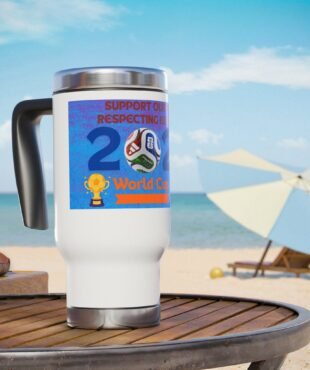 White insulated mug with a blue World Cup sticker on a beach table, ocean in the background.