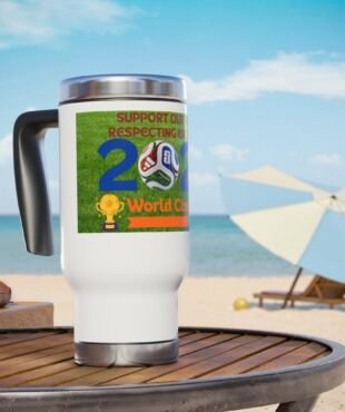 White travel mug on a wooden table at the beach, featuring a World Cup graphic and soccer ball motif on a green label.