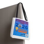 White tote bag with a blue World Cup poster design hanging from black handles against a white background, showing soccer imagery and text.